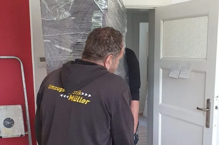umzugshelfer manovriert verpacktes moebel durch tuerrahmen